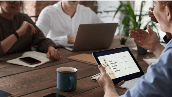 powerpoint presentation create online Photograph of 3 people gathered together talking about a report with a tablet